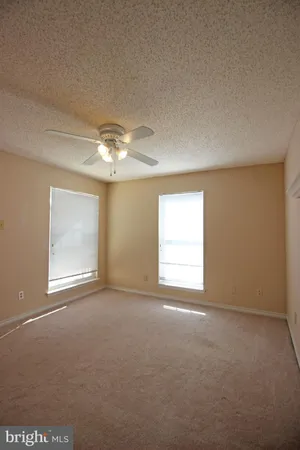 en empty room with windows and chandelier fan