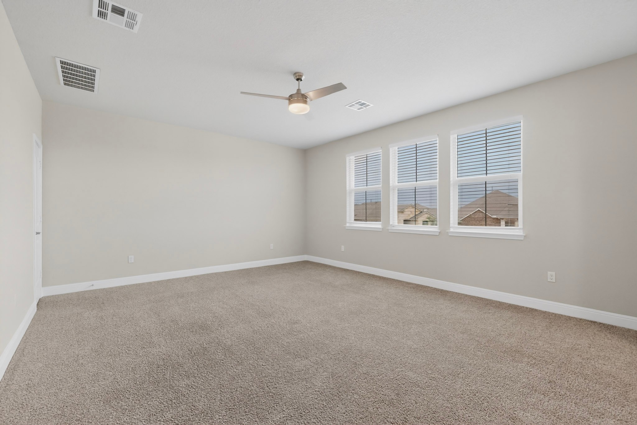 16809 Guido Cove Pflugerville, TX 78660 - Photo 22 of 40 Spacious room featuring neutral paint, carpeted flooring, three windows with blinds, a ceiling fan with integrated lighting, and white trim molding