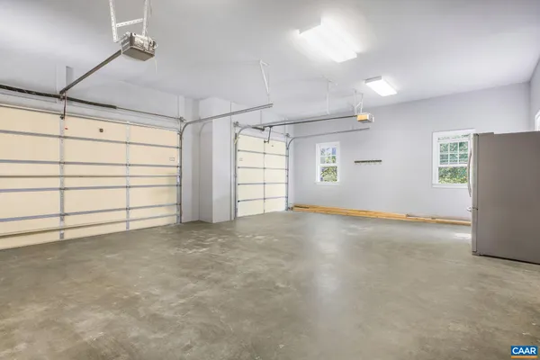 an empty room with chandelier fan and windows