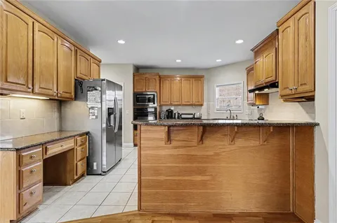 a kitchen with stainless steel appliances granite countertop a refrigerator a stove a sink and a microwave