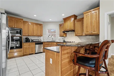 a kitchen with stainless steel appliances granite countertop a stove top oven a refrigerator a sink and a granite counter tops