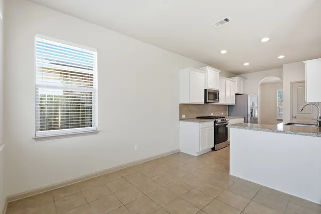 a view of a kitchen with kitchen island a sink stainless steel appliances and cabinets