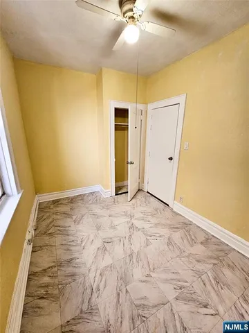 a view of an empty room with wooden floor and a ceiling fan