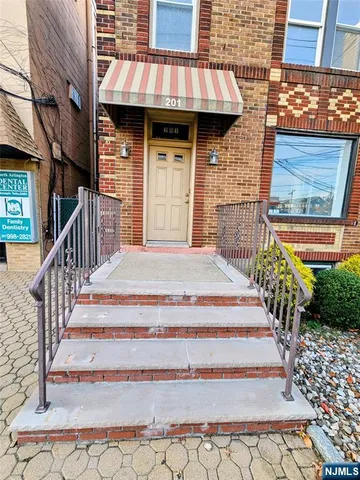 a view of a brick house with large windows and wooden fence