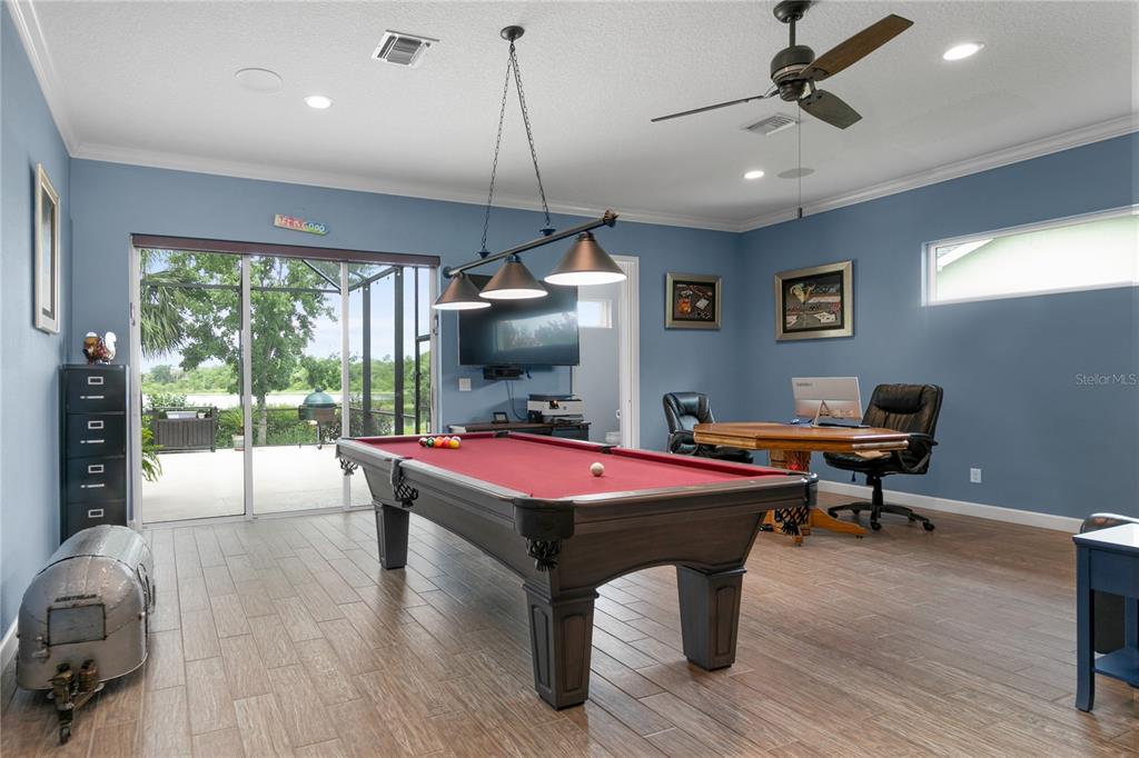 8065 Bridgeport Bay Circle Mount Dora, FL 32757 - Photo 26 of 60 a room with furniture pool table flat screen tv and a floor to ceiling window