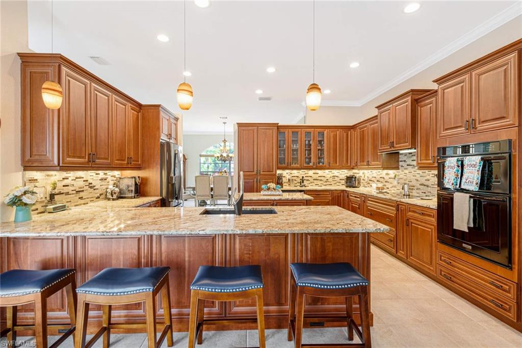 2035 Teagarden Lane Naples, FL 34110 - Photo 5 of 21 a kitchen with granite countertop wooden cabinets and stainless steel appliances