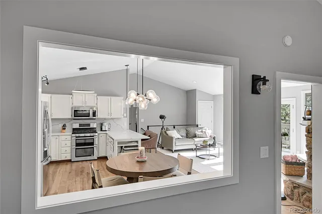 a dining room with wooden floor a chandelier a wooden table and chairs