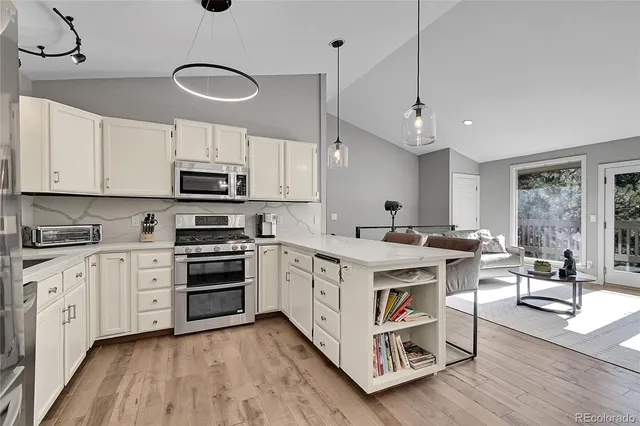 a kitchen with stainless steel appliances a white stove top oven a sink dishwasher and a refrigerator