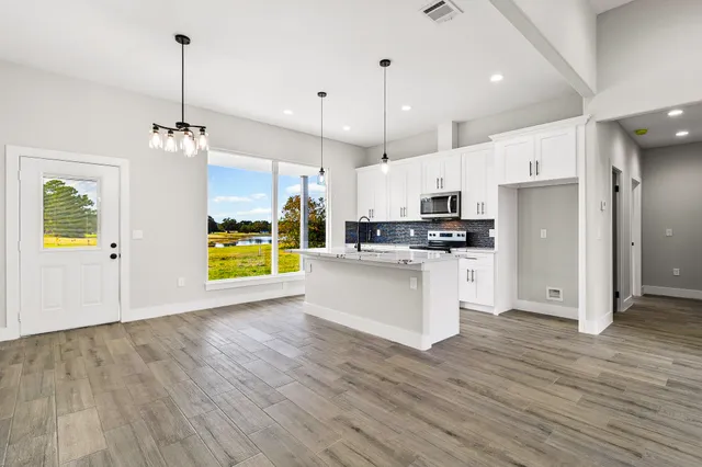 a view of kitchen with stainless steel appliances granite countertop cabinets and wooden floor