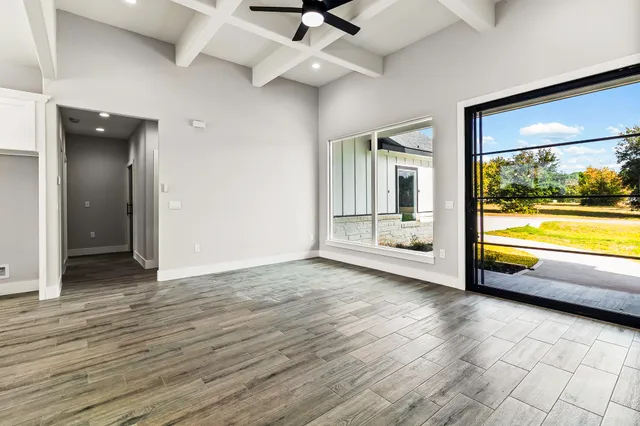 a view of an empty room with window and wooden floor