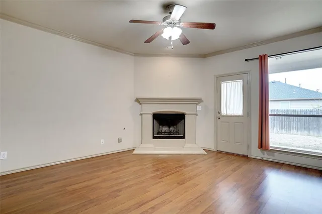 a view of an empty room with a fireplace and wooden floor