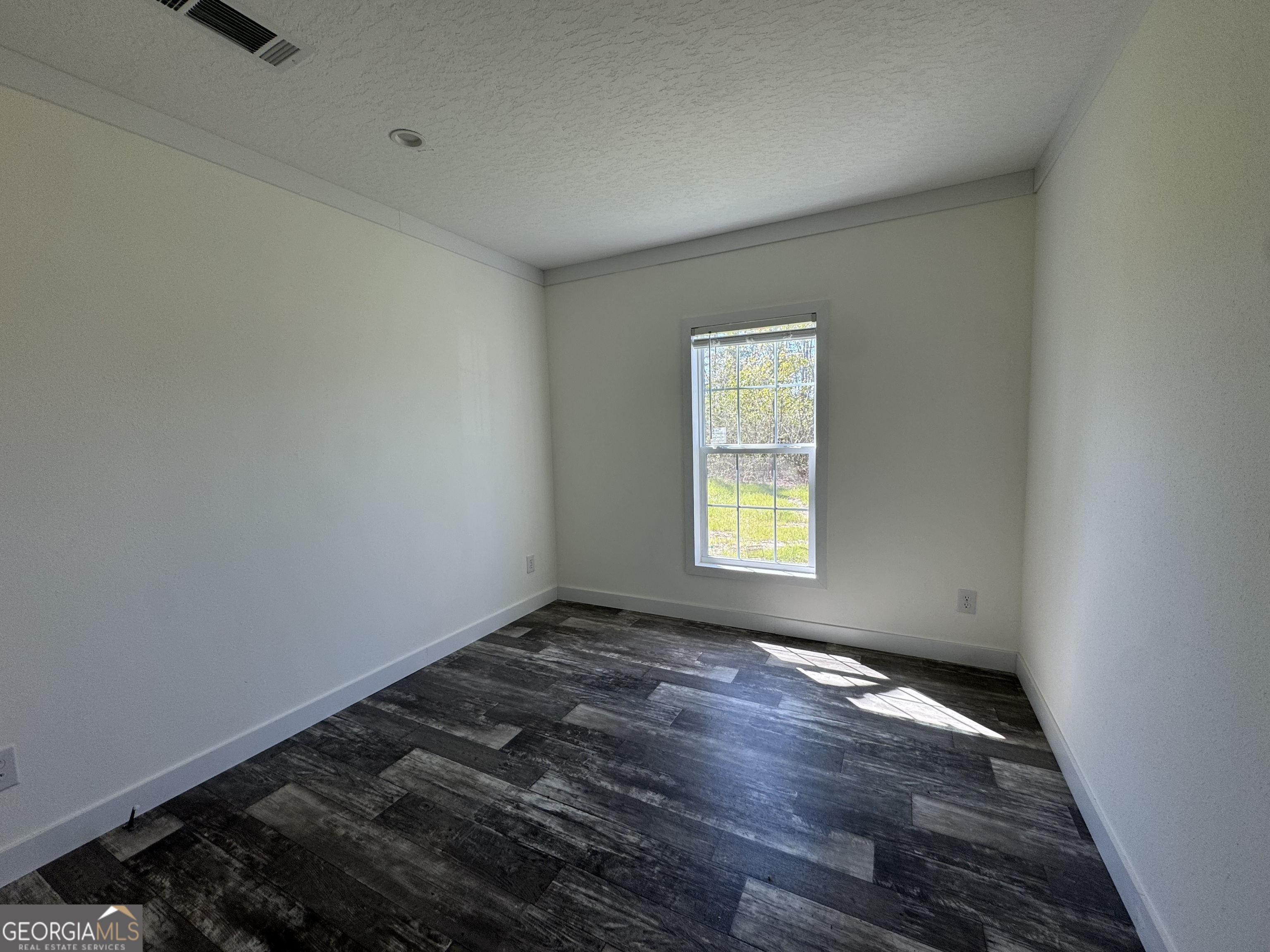 1505 West 4th St Extension Alma, GA 31510 - Photo 14 of 22 an empty room with wooden floor and windows