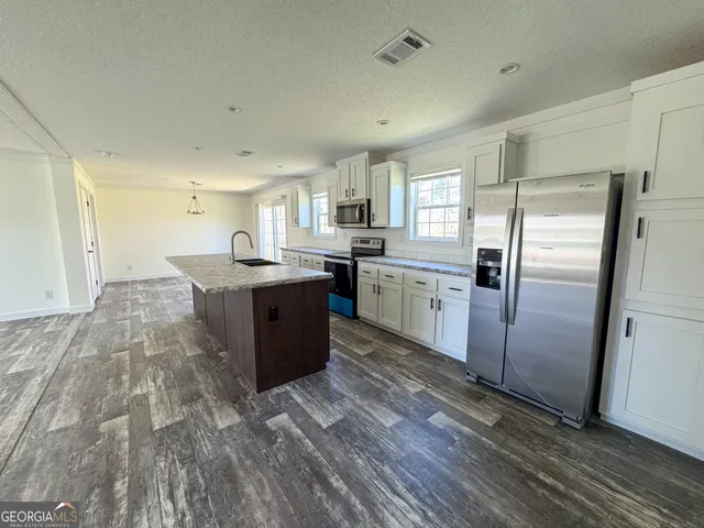 a kitchen with stainless steel appliances granite countertop a refrigerator a sink dishwasher a stove with wooden floors