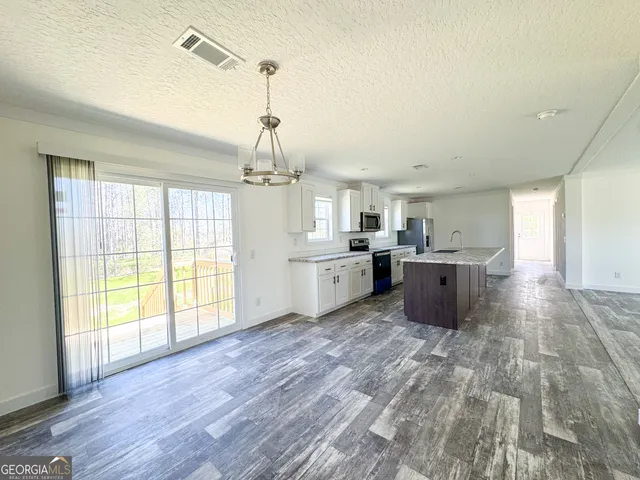 a view of a big room with wooden floor and windows