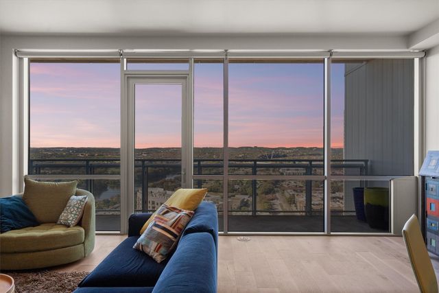 a view of a dining room with furniture a chandelier and large windows