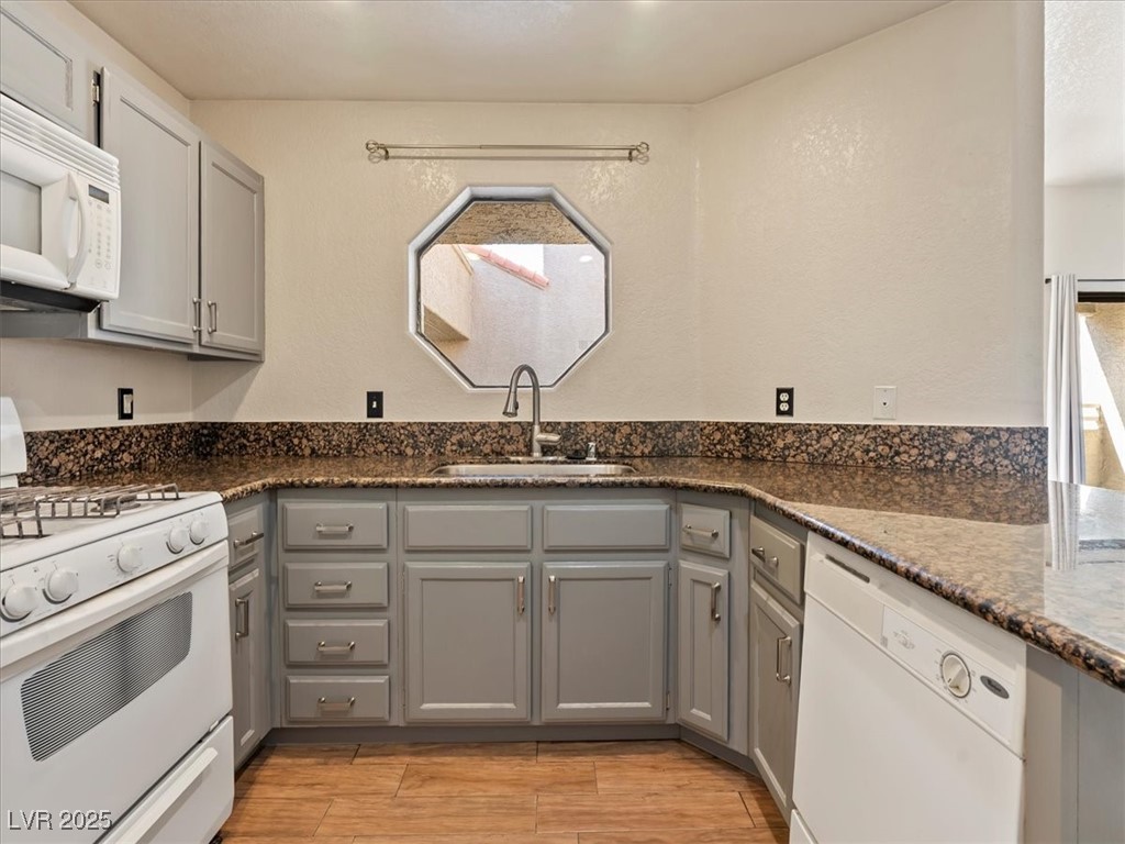 5052 South Rainbow Boulevard, Unit 201 Las Vegas, NV 89118 - Photo 11 of 24 Kitchen with gray cabinets, white appliances, and dark stone countertops