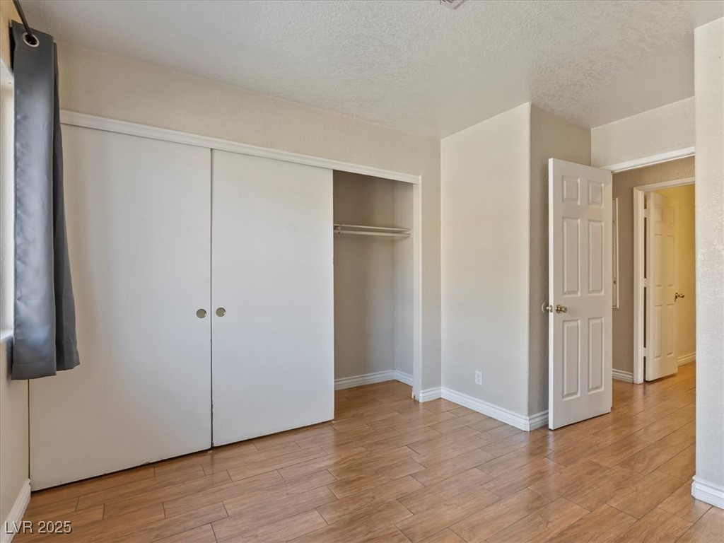 5052 South Rainbow Boulevard, Unit 201 Las Vegas, NV 89118 - Photo 13 of 24 Unfurnished bedroom featuring a textured ceiling, light wood finished floors, and a closet