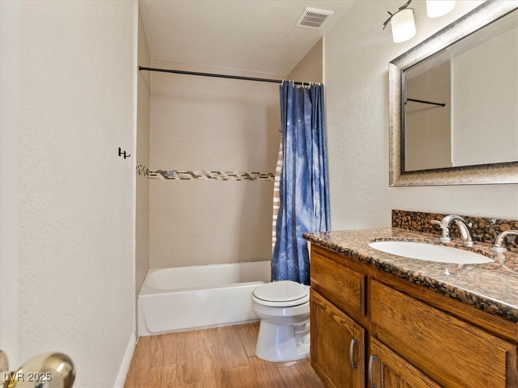 5052 South Rainbow Boulevard, Unit 201 Las Vegas, NV 89118 - Photo 14 of 24 Full bath with vanity, light wood-type flooring, a textured wall, and shower / tub combo with curtain