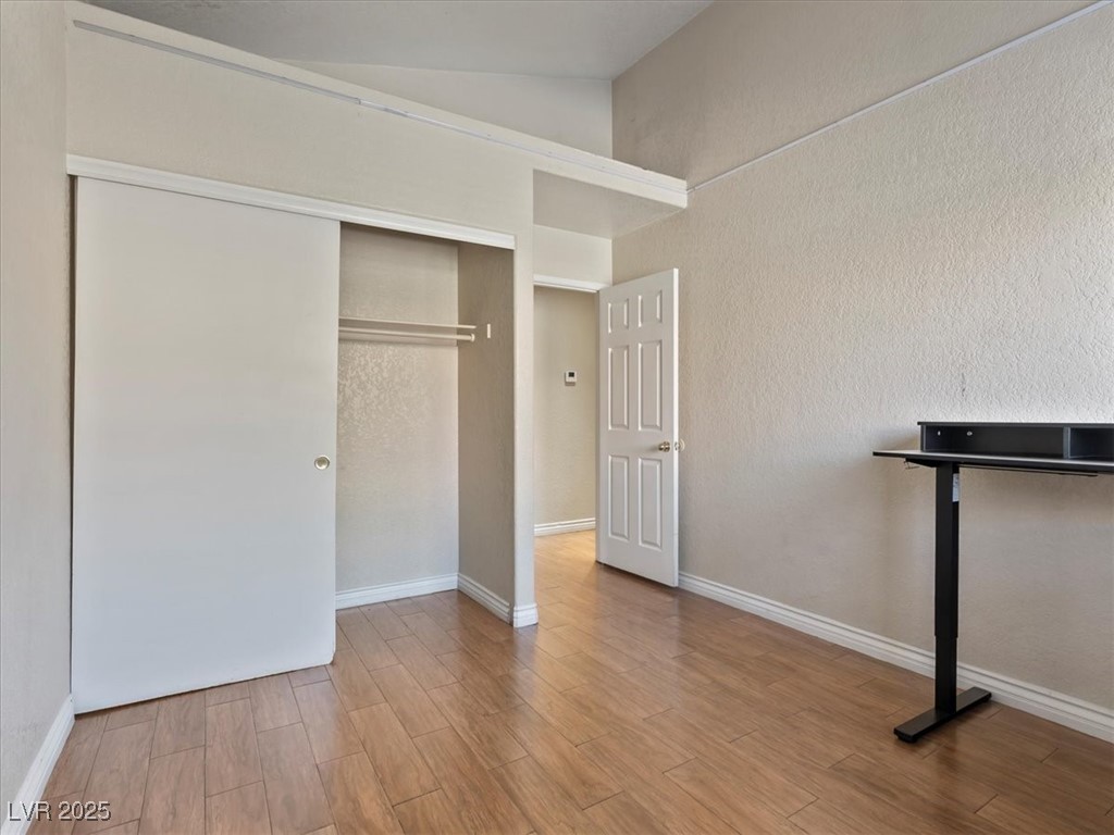 5052 South Rainbow Boulevard, Unit 201 Las Vegas, NV 89118 - Photo 17 of 24 Unfurnished bedroom with light wood-type flooring, a closet, and vaulted ceiling