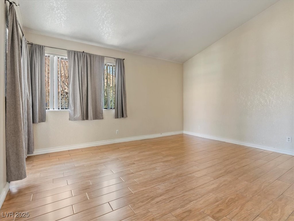 5052 South Rainbow Boulevard, Unit 201 Las Vegas, NV 89118 - Photo 18 of 24 Spare room with light wood-style flooring, a textured ceiling, and lofted ceiling