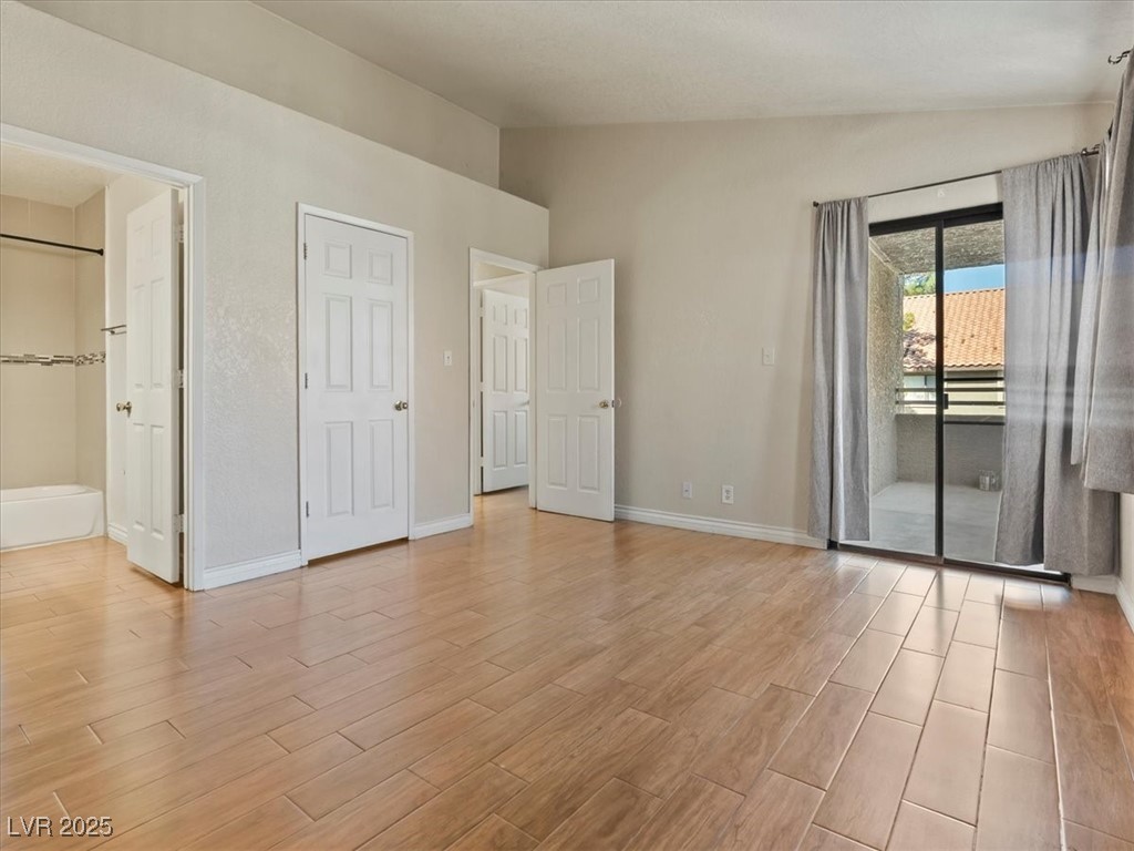 5052 South Rainbow Boulevard, Unit 201 Las Vegas, NV 89118 - Photo 19 of 24 Unfurnished bedroom with vaulted ceiling, wood finish floors, and access to outside