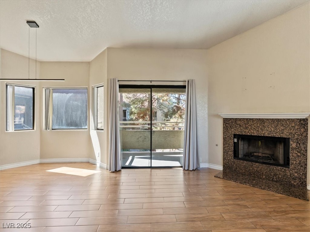 5052 South Rainbow Boulevard, Unit 201 Las Vegas, NV 89118 - Photo 7 of 24 Unfurnished living room featuring a textured ceiling, a high end fireplace, and light wood-style flooring
