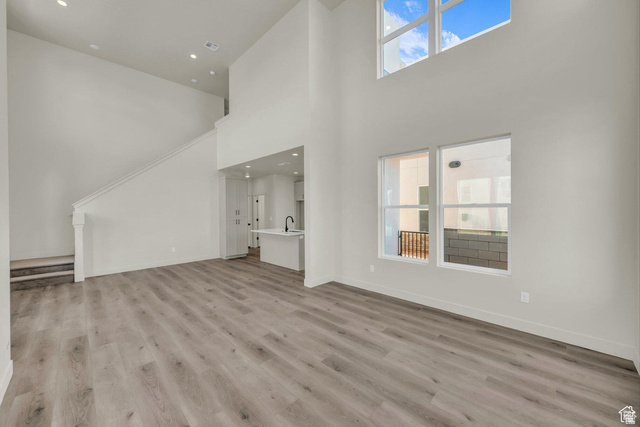 560 Aqua Cove St. George, UT 84790 - Photo 5 of 27 Unfurnished living room featuring plenty of natural light, a high ceiling, light wood-style flooring, and recessed lighting