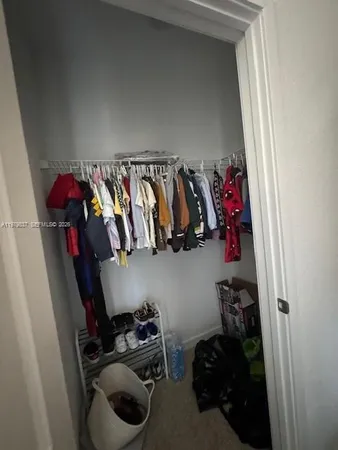 a view of walk in closet with clothes and shoes