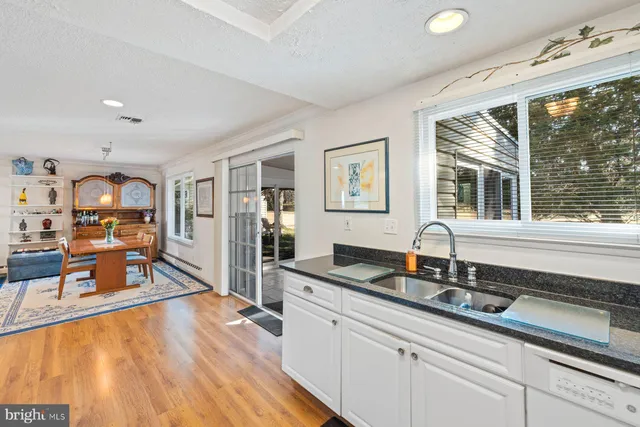 a kitchen with granite countertop a sink and white cabinets with wooden floor