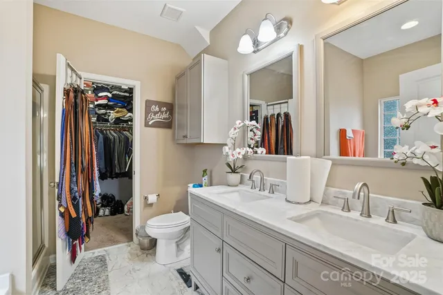 a bathroom with a granite countertop sink vanity mirror and toilet