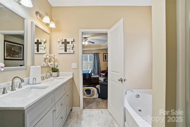 a en suite bathroom with a granite countertop tub sink and mirror