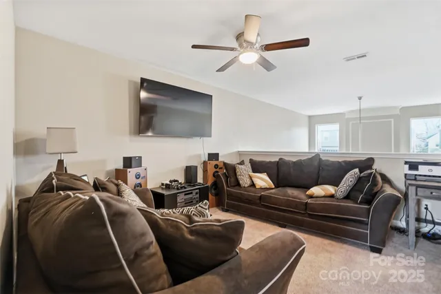 a living room with furniture a ceiling fan and a flat screen tv