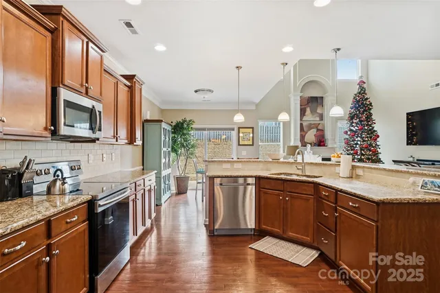a large kitchen with stainless steel appliances granite countertop a sink a stove counter space and cabinets