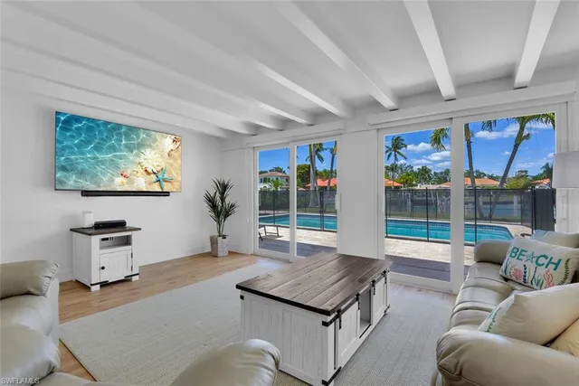 a living room with furniture a flat screen tv and a large window