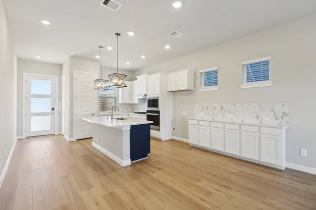 a large white kitchen with kitchen island a sink a center island stainless steel appliances and a cabinets