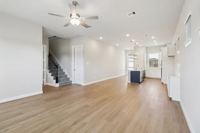 a view of an empty room with wooden floor and a ceiling fan