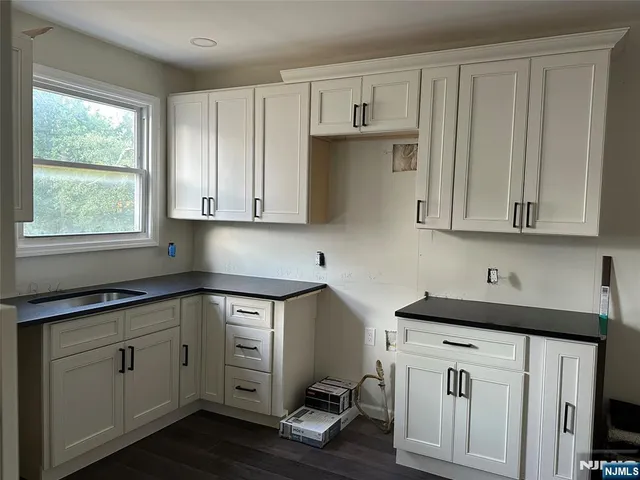 a kitchen with stainless steel appliances granite countertop a sink dishwasher a stove and white cabinets with wooden floor