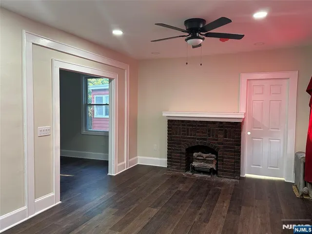 an empty room with wooden floor a fireplace and a window