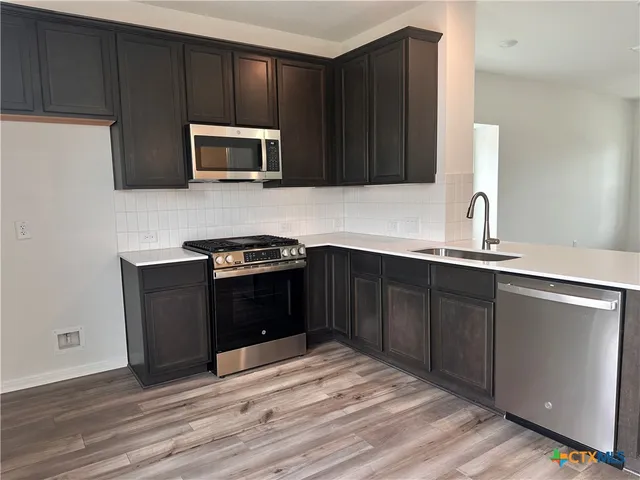 a kitchen with granite countertop wooden cabinets and black stainless steel appliances