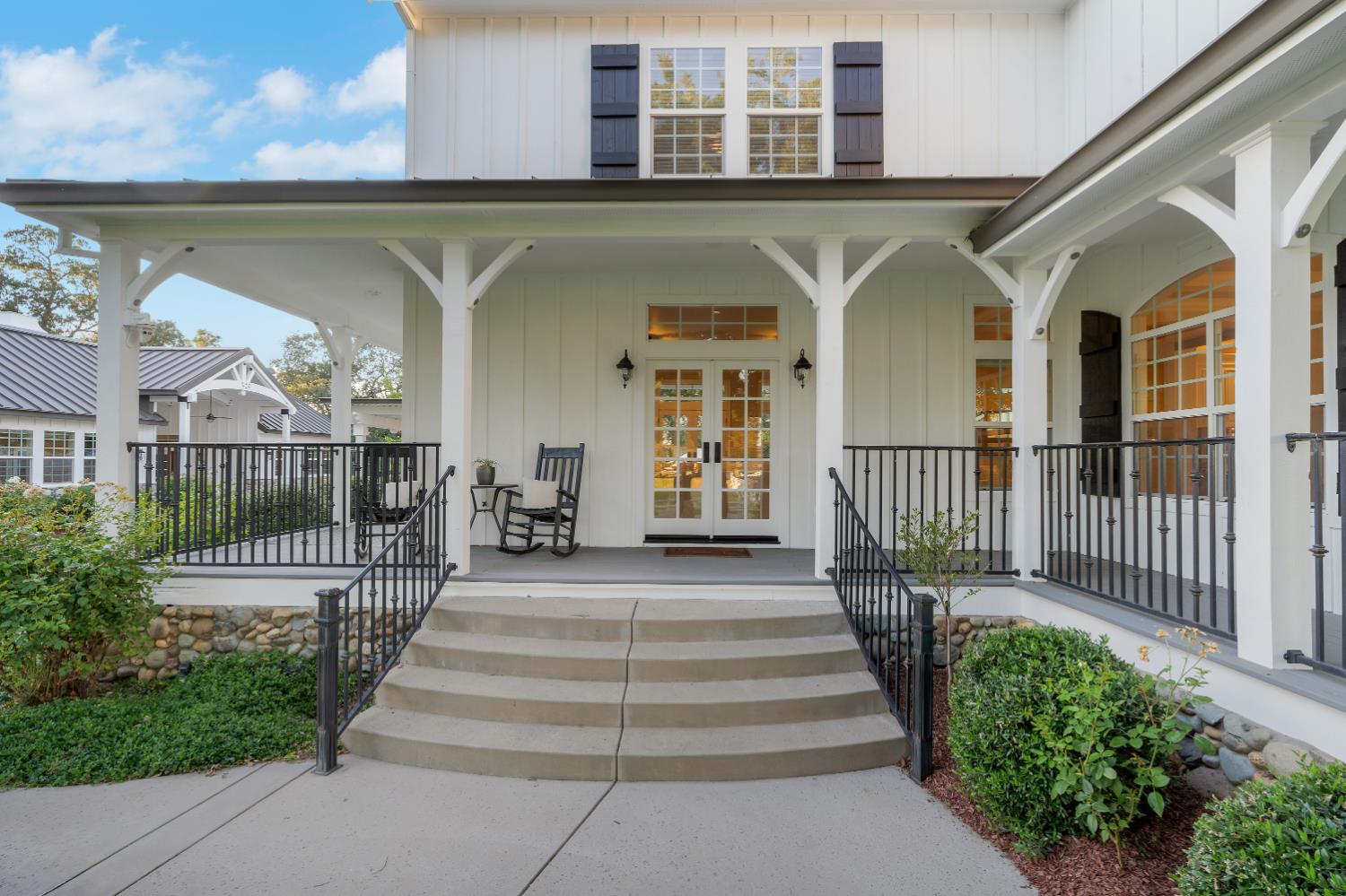 2905 Virginiatown Road Lincoln, CA 95648 - Photo 54 of 86 Expansive covered porch featuring a board and batten facade, stone foundation, concrete steps with wrought iron railings, and double glass-paned entry doors