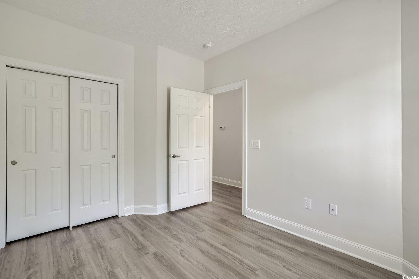 1113 Peace Pipe Place, Unit 204 Myrtle Beach, SC 29579 - Photo 20 of 27 Unfurnished bedroom featuring light wood-type flooring, a textured ceiling, and a closet