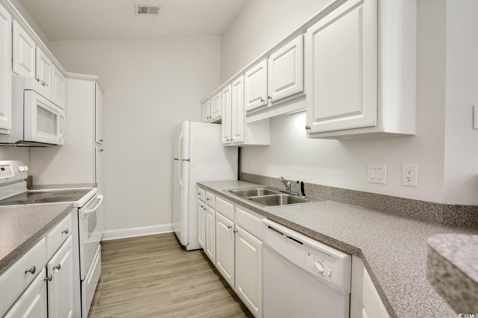 1113 Peace Pipe Place, Unit 204 Myrtle Beach, SC 29579 - Photo 4 of 27 Kitchen featuring white appliances, white cabinetry, light wood finished floors, and light countertops