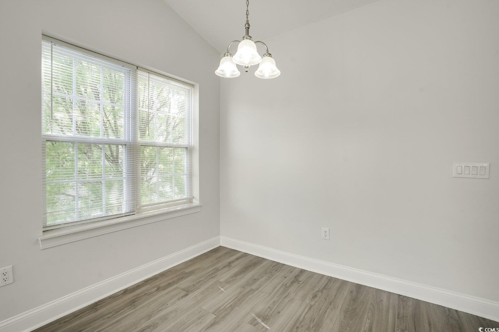1113 Peace Pipe Place, Unit 204 Myrtle Beach, SC 29579 - Photo 7 of 27 Empty room with a chandelier, wood finished floors, and vaulted ceiling