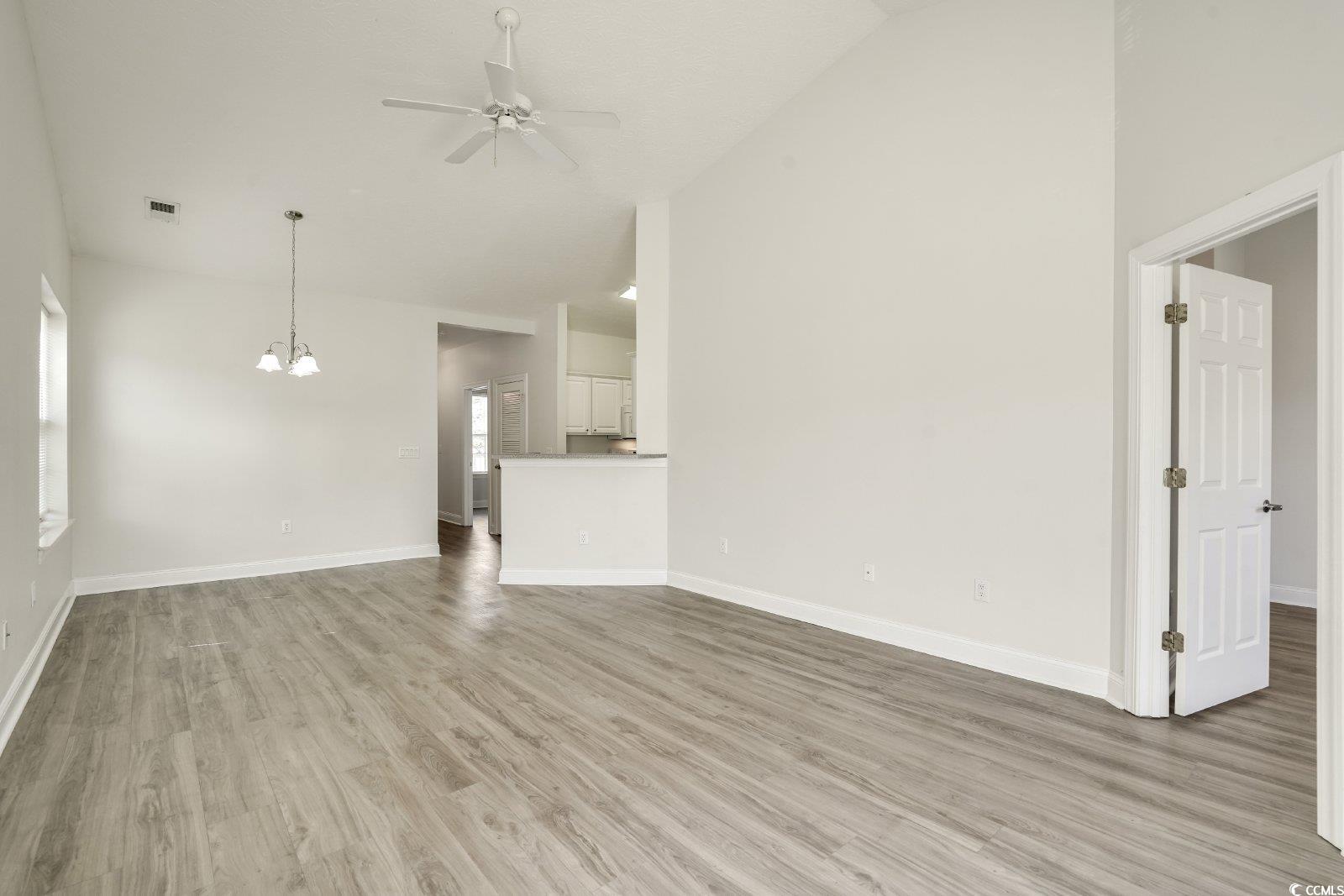 1113 Peace Pipe Place, Unit 204 Myrtle Beach, SC 29579 - Photo 9 of 27 Unfurnished living room featuring ceiling fan, high vaulted ceiling, light wood-type flooring, and a chandelier