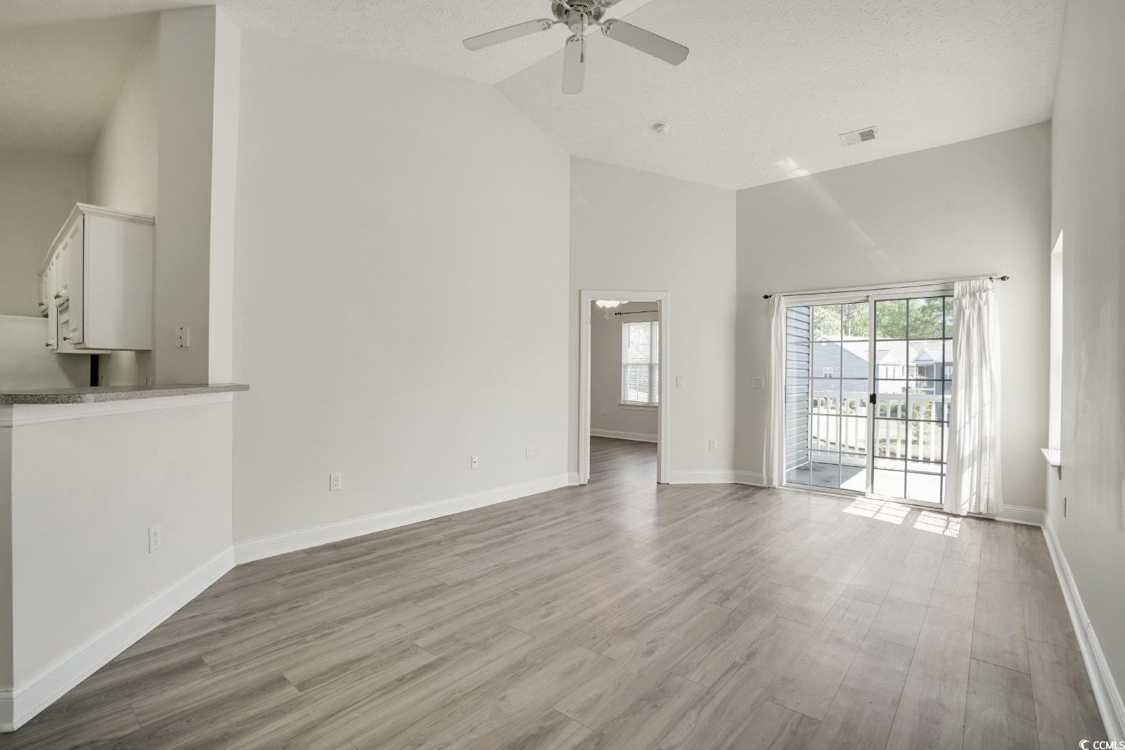 1113 Peace Pipe Place, Unit 204 Myrtle Beach, SC 29579 - Photo 10 of 27 Unfurnished living room featuring high vaulted ceiling, a textured ceiling, a ceiling fan, and light wood-style floors