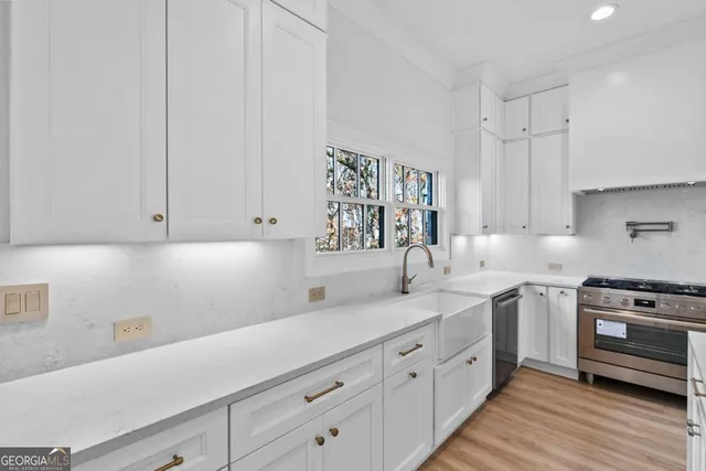 a kitchen with stainless steel appliances a stove a sink a center island and wooden floor