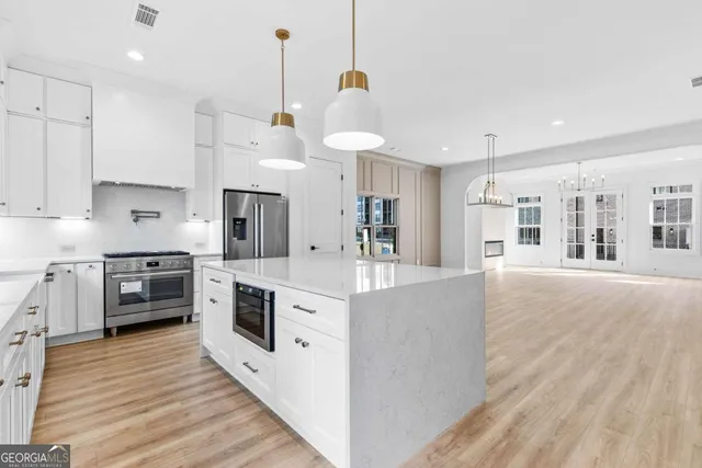 a view of a room with wooden floor kitchen and windows