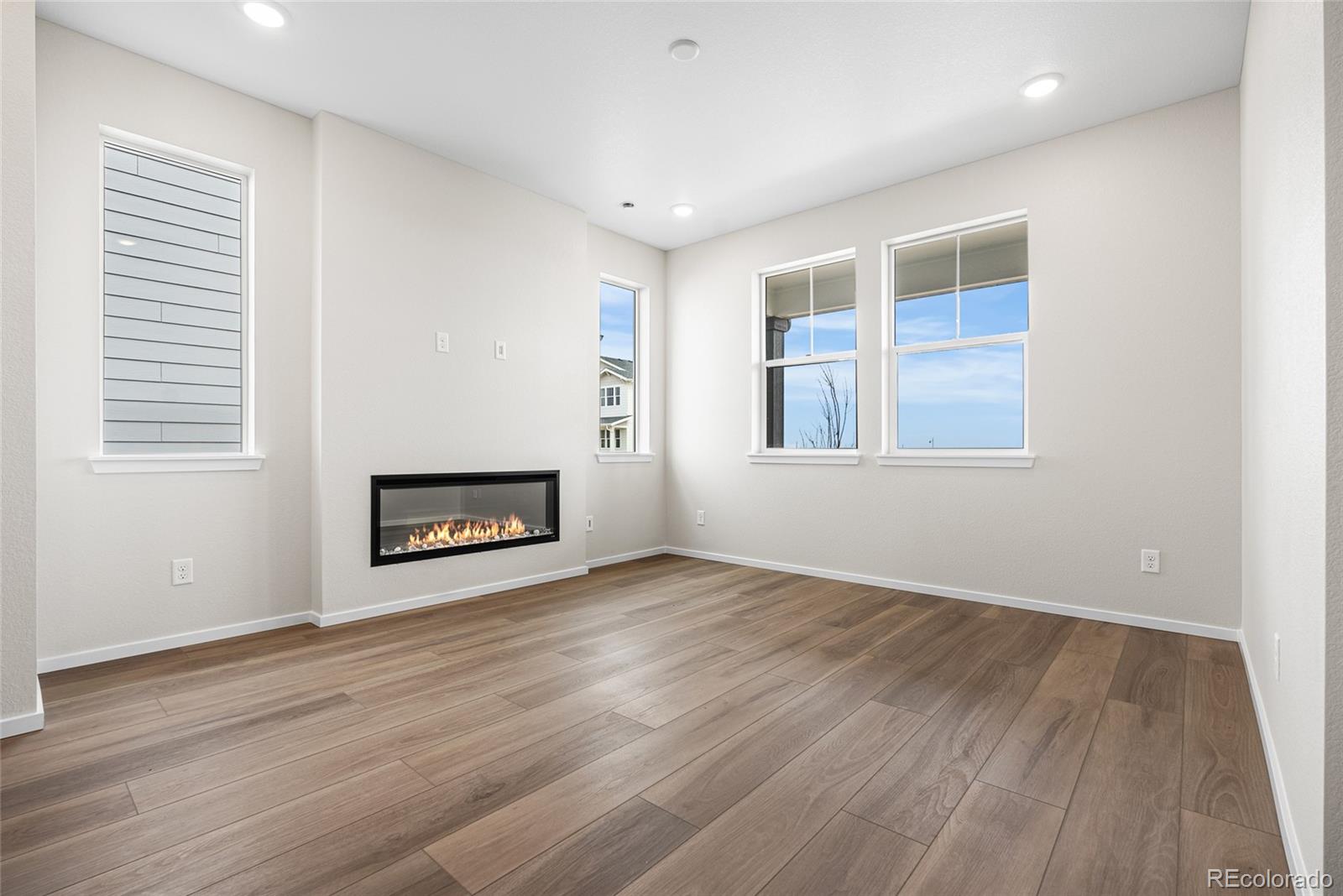 13181 Front Porch Lane Firestone, CO 80504 - Photo 11 of 34 an empty room with wooden floor a fireplace and windows