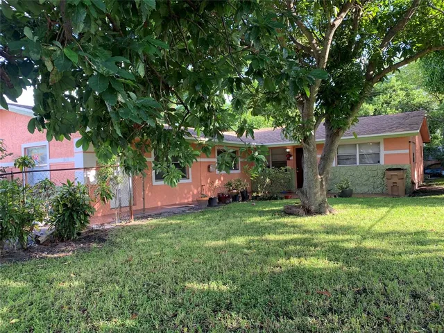 a backyard of a house with table and chairs and a large tree