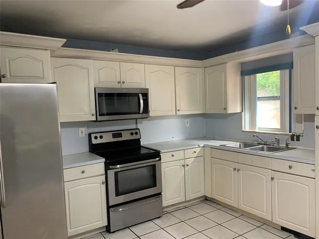 a kitchen with white cabinets appliances and a window